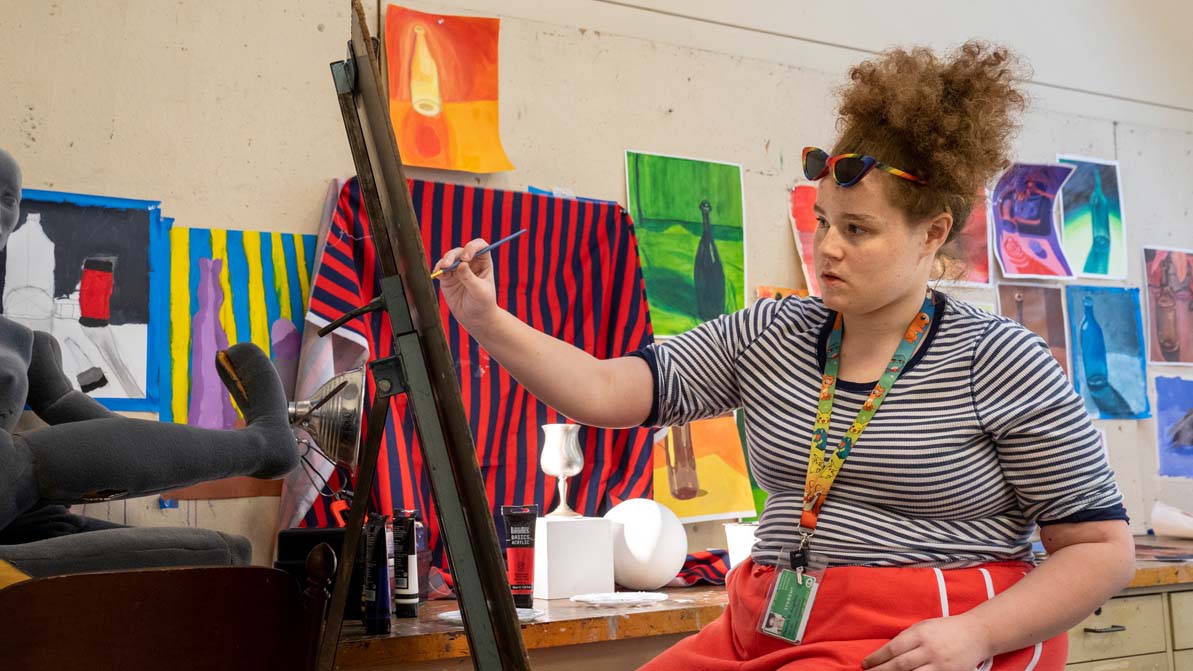 A student paints using an easel